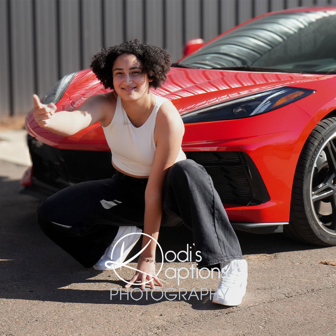 senior posing with red car