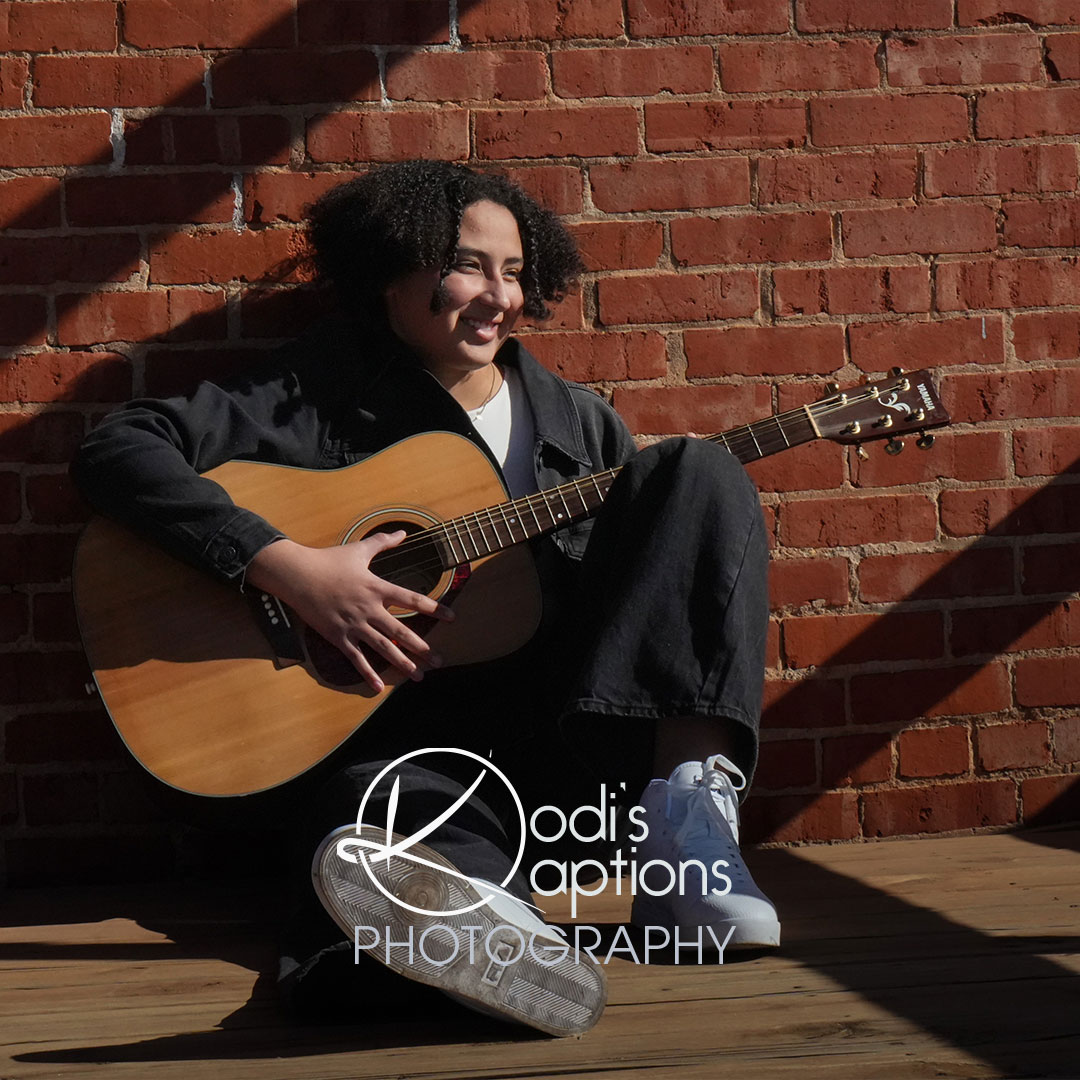 senior girl posing with guitar on brink wall